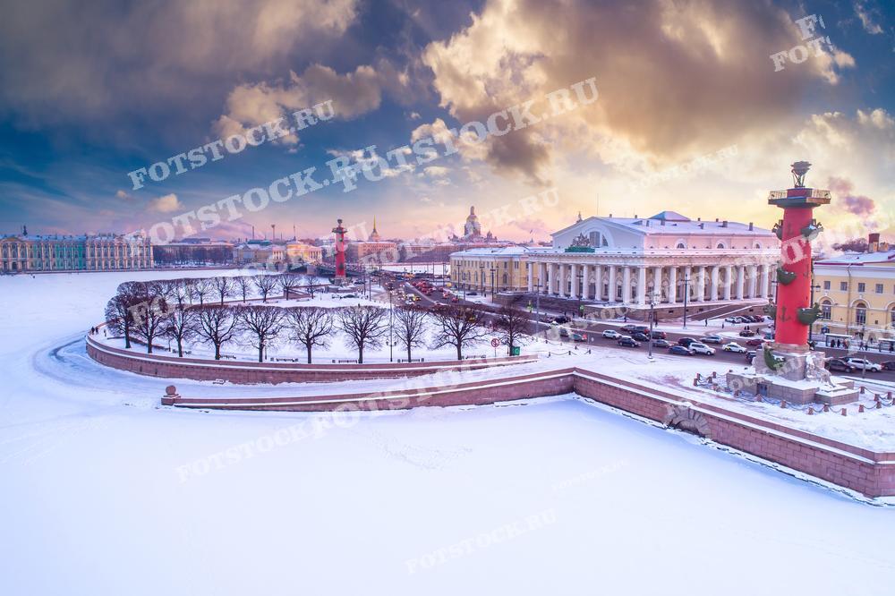 Фотография показывает зимний вечер на Стрелке Васильевского острова в Санкт-Петербурге. На снимке отчетливо видны Ростральные колонны и здание Биржи. Этот снимок идеально подходит для использования в рекламных кампаниях, публикациях о зимних праздниках, а также в качестве иллюстрации для статей о зимнем Петербурге.